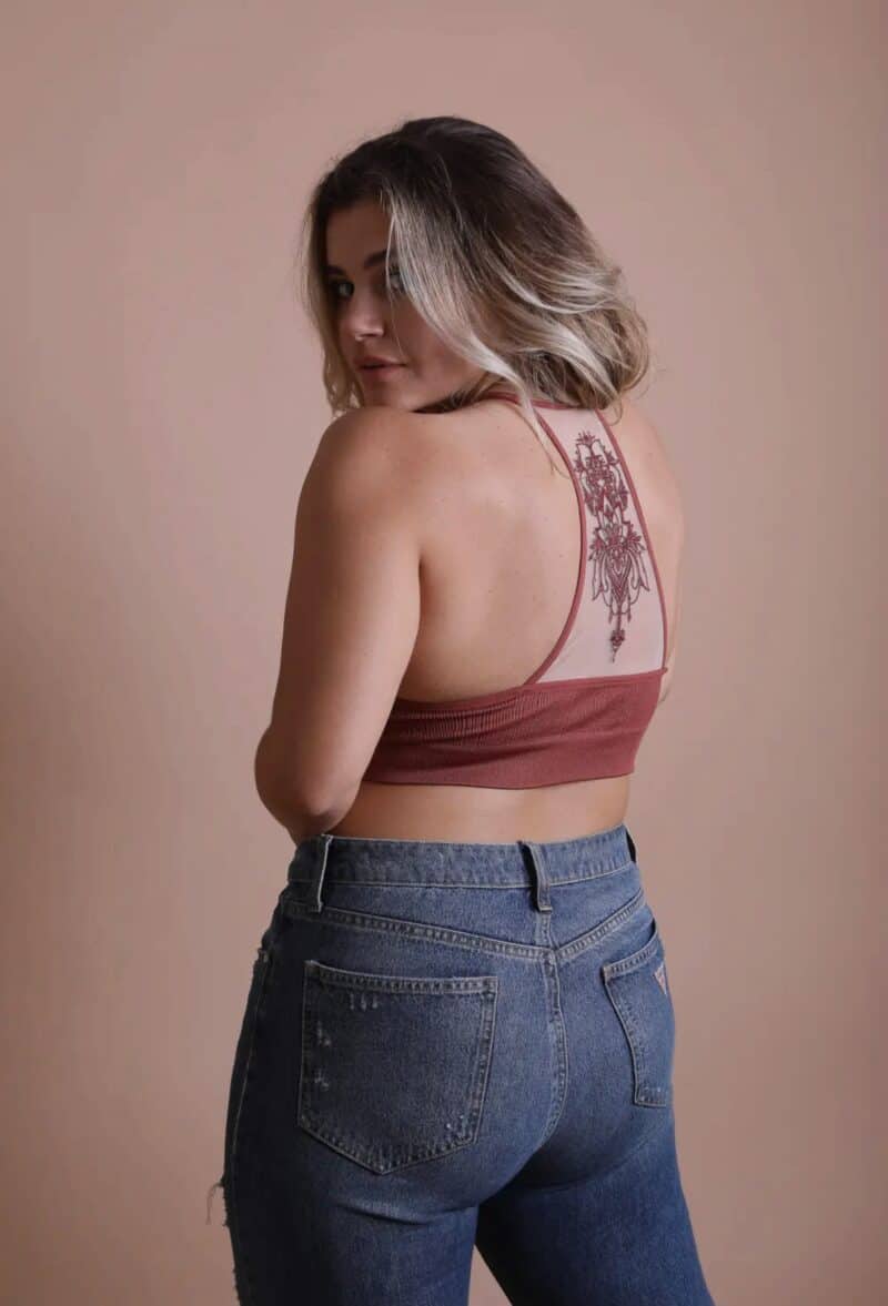 Woman with a tattoo on her back looking over her shoulder.
